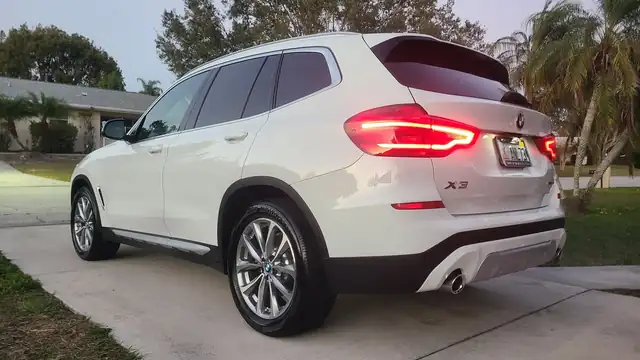 White BMW X3 rear quarter after a detail, palms behind