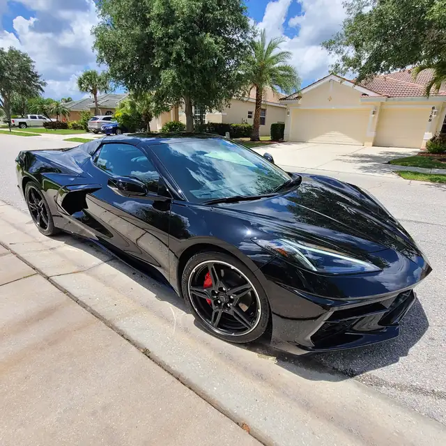 Black Corvette Stingray convertible on a driveway after an exterior detail