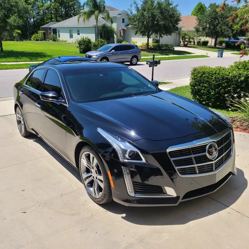 Black Cadillac CTS on a Bradenton driveway, clear coat sealed and reflecting the trees